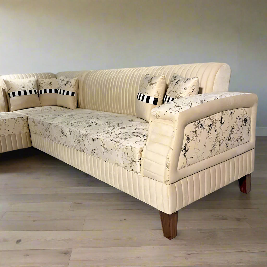 Beige patterned sectional sofa with decorative pillows on a marble floor, branded 'Lahore Furniture'.